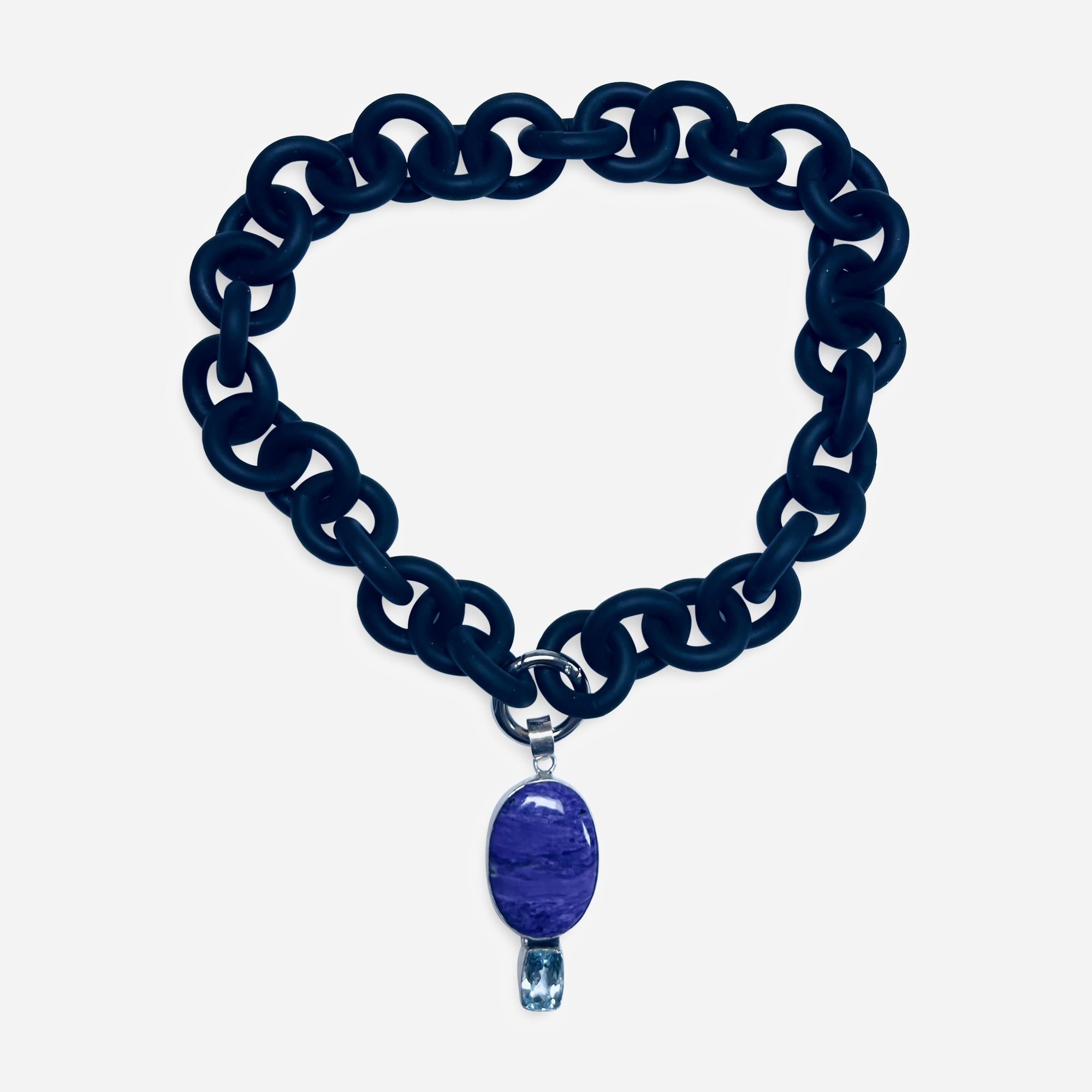BLACK RUBBER NECKLACE WITH PENDENT BEZEL SET IN SILVER WITH A LARGE CHAROITE STONE AND A LIGHT BLUE TOPAZ STONE.