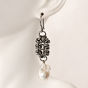  chainmail dangle earring with a baroque pearl pendant, displayed on a white mannequin ear.