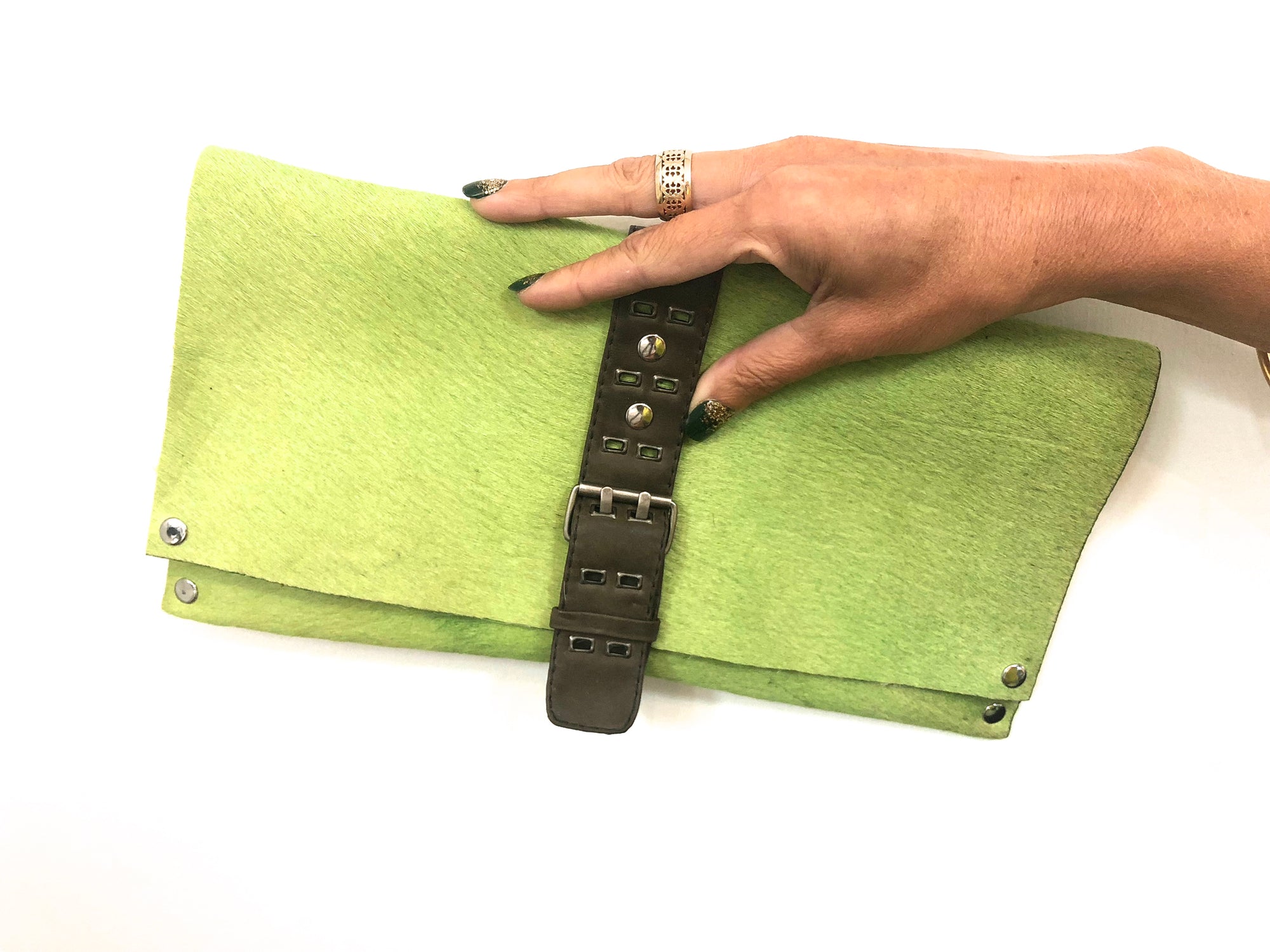 GREEN HAIR-ON COWHIDE CLUTCH WITH DETAILED UTILITY LEATHER STRAP AND BELT BUCKLE-STYLE CLOSURE by nyet jewelry